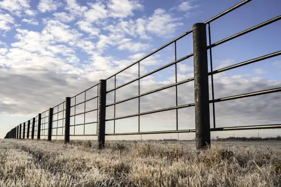 A finished composite post fence line under open sky