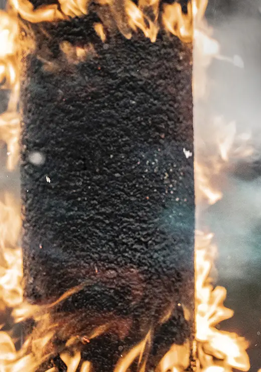 A Generations composite fencepost held in a torch flame during a fire test